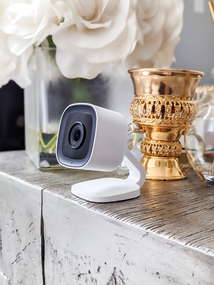 A stylish home security camera on a decorative table with elegant gold accents and floral decor.