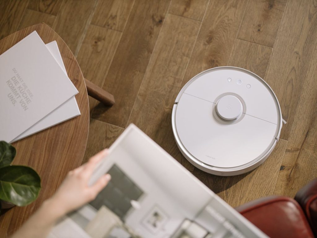 A sleek robot vacuum cleaner operating on a wooden floor, symbolizing modern home technology.